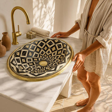 Handmade oval brass bathroom sink with bone and resin flower pattern inlay on black base