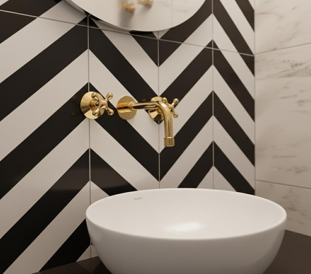 Bathroom sink with gold faucet against a black and white chevron tiled wall.
