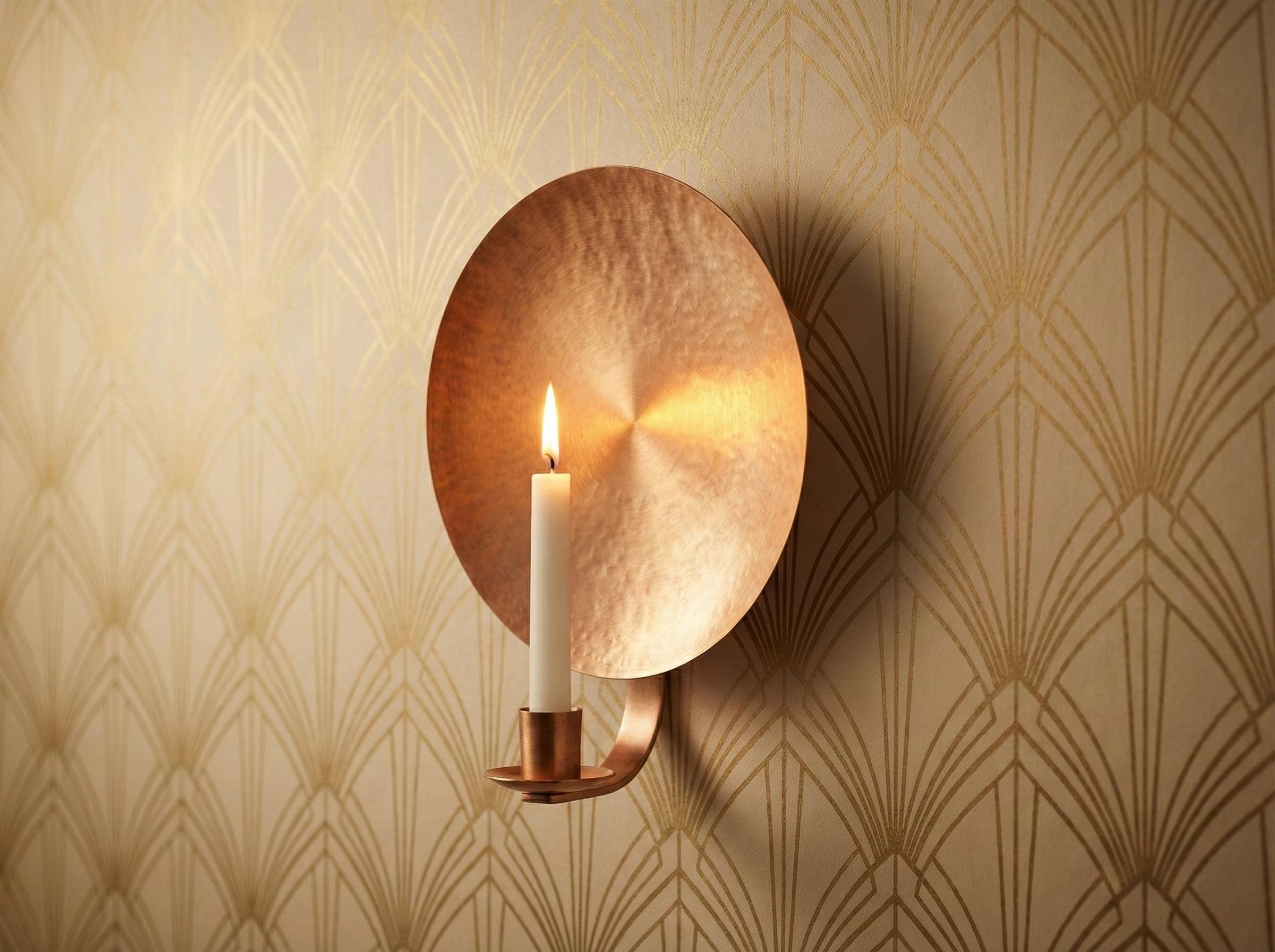 Copper wall sconce with a lit candle on a patterned wall