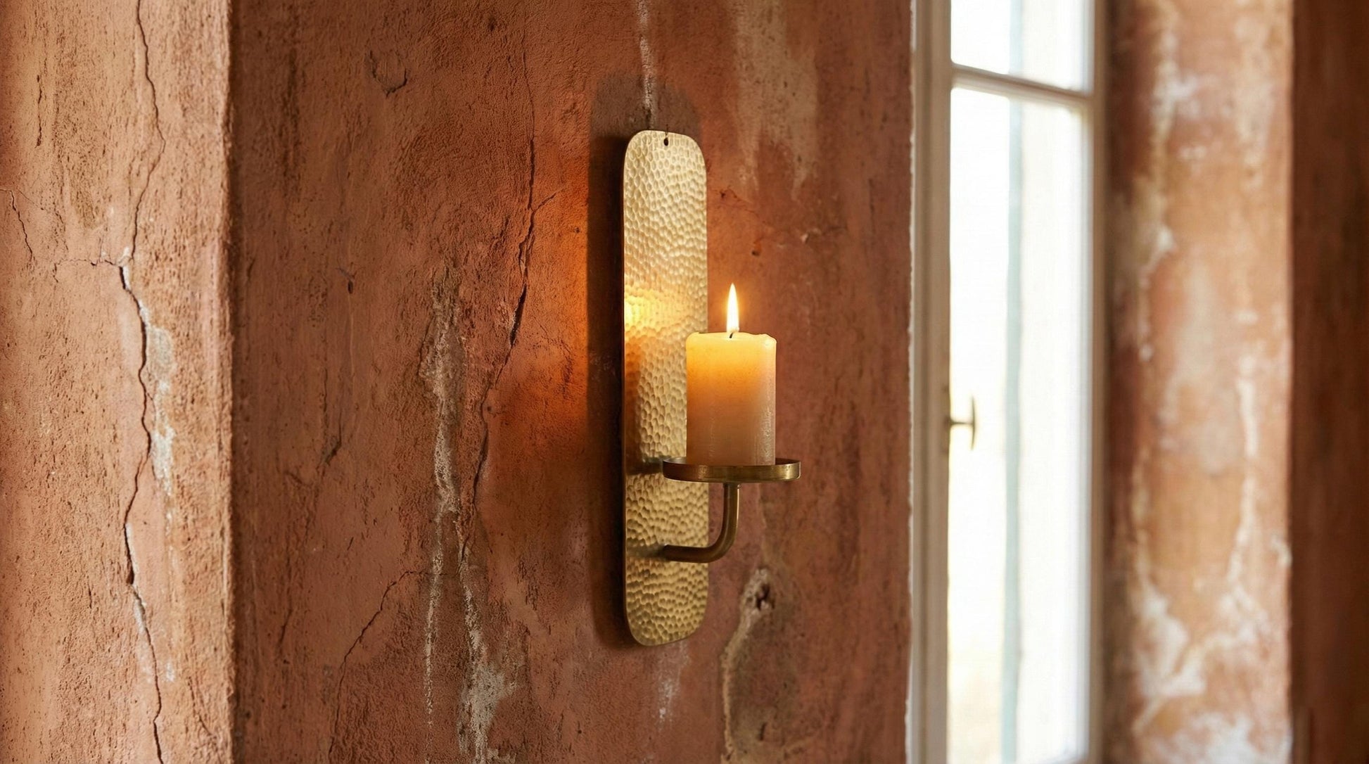 Wall-mounted candle holder with a candle on a textured wall