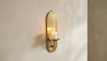 Brass wall sconce with candle on a beige wall