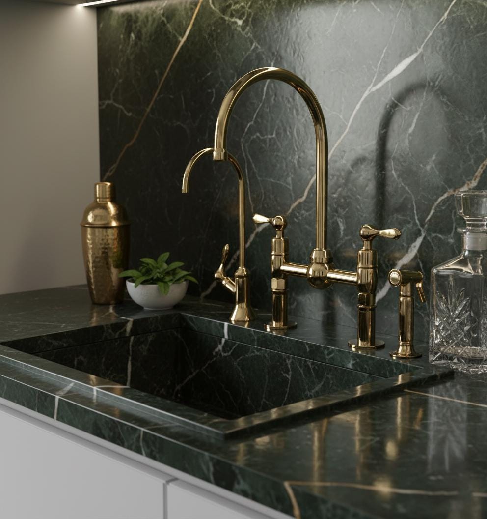Gold kitchen faucet and handles on a black marble countertop with a dark marble backsplash.