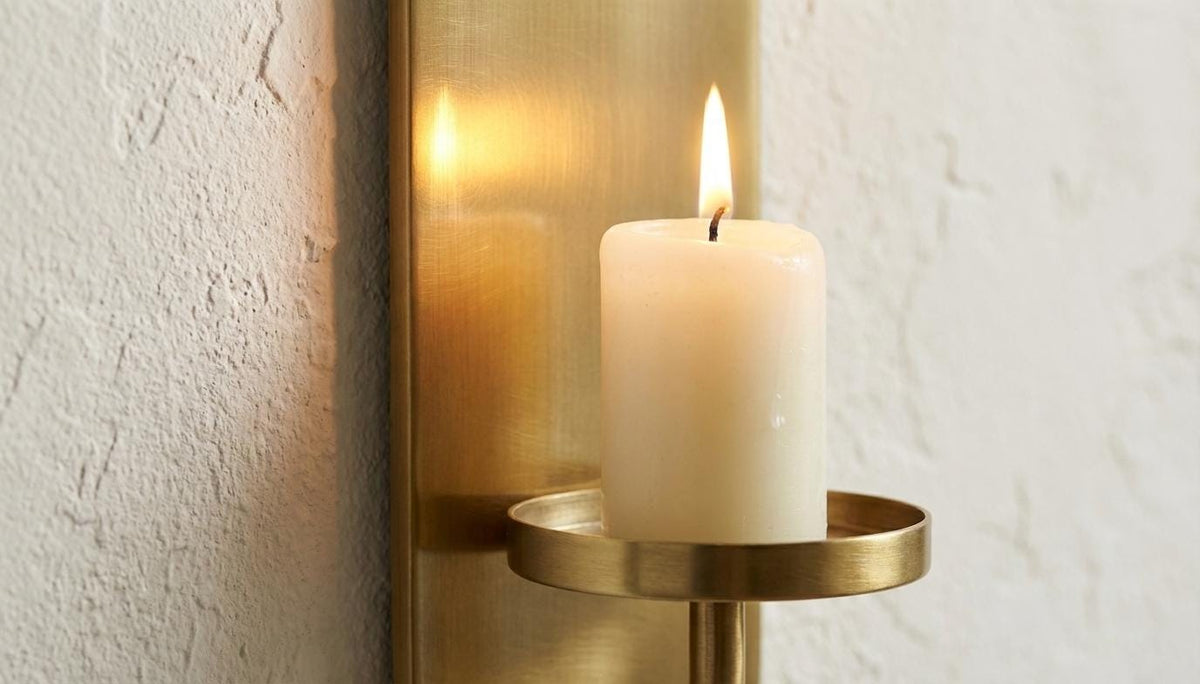 Candle in a brass holder against a textured wall