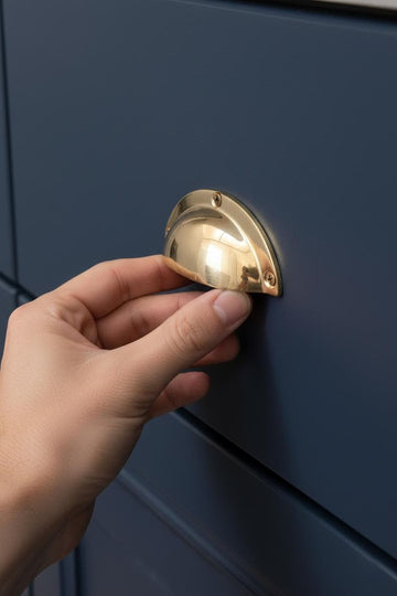 Hand opening a blue cabinet with a gold handle