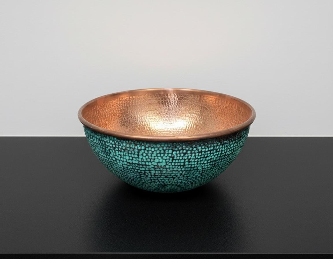 Copper and turquoise mosaic bowl on a black surface with a gray background