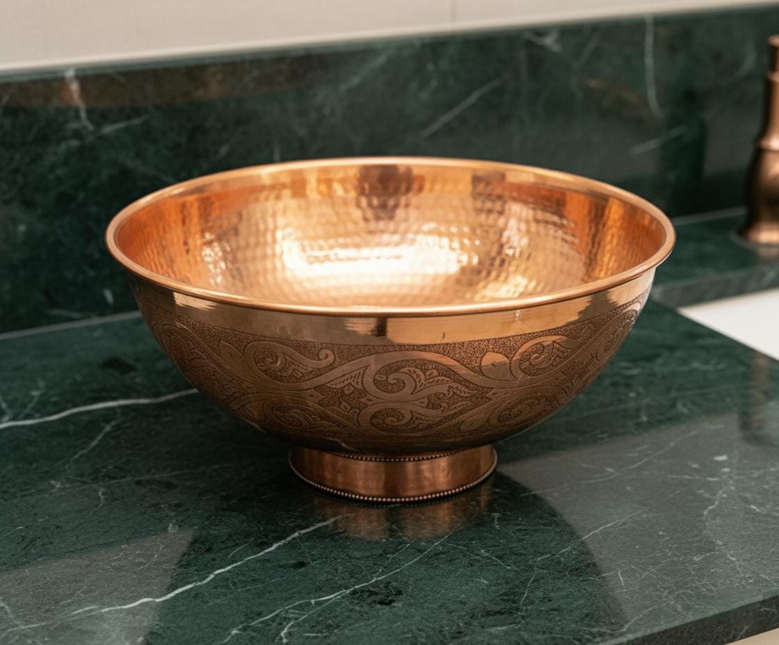 Copper bowl with embossed design on a green marble surface
