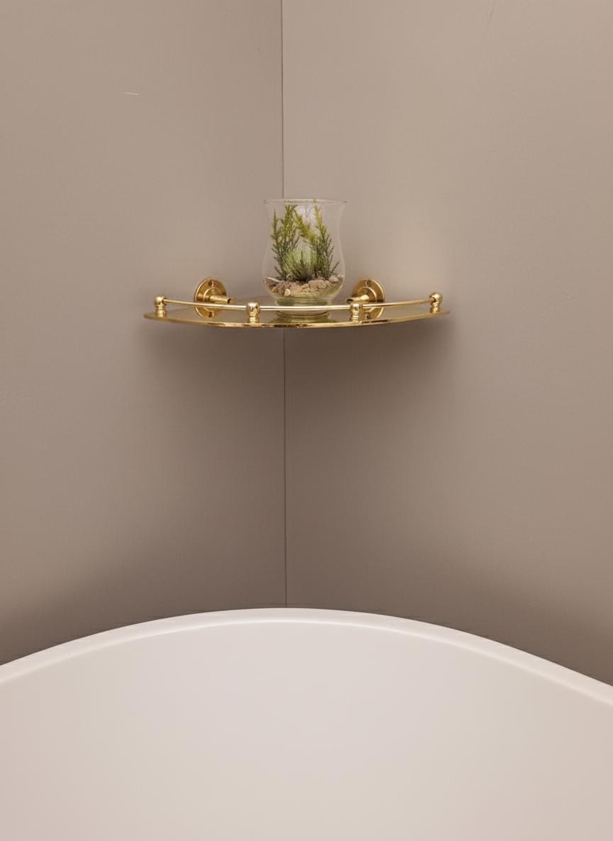 Gold corner shelf with a small plant against a beige wall