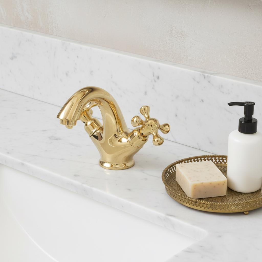 Gold faucet on a marble countertop with soap and a soap dispenser.