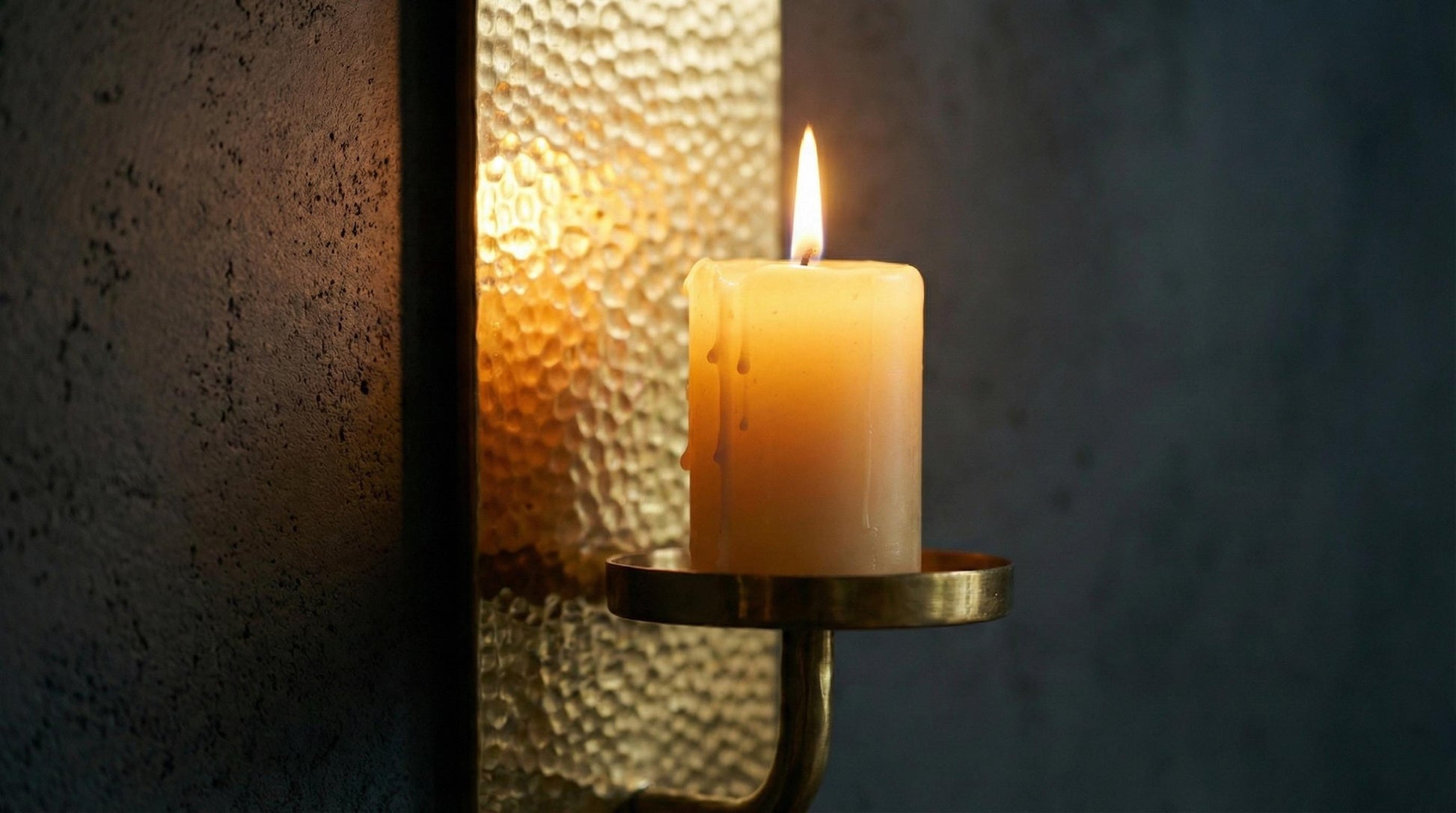 Candle in a brass holder with a textured wall background