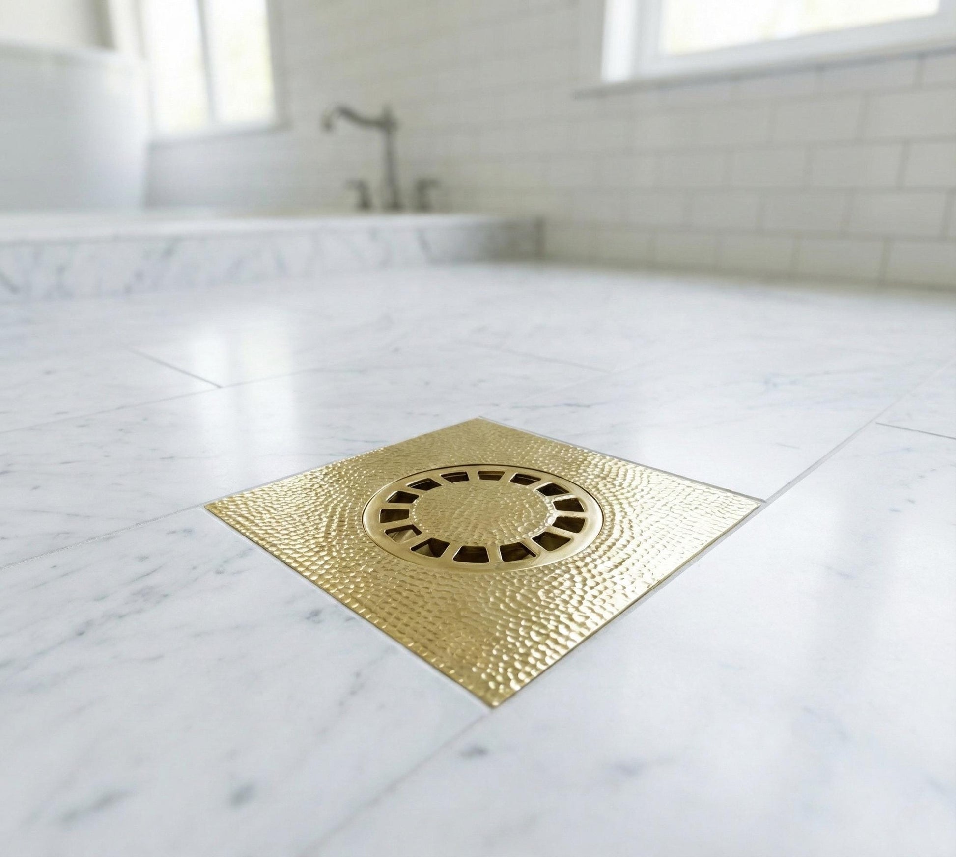 Gold shower drain cover on a marble bathroom floor