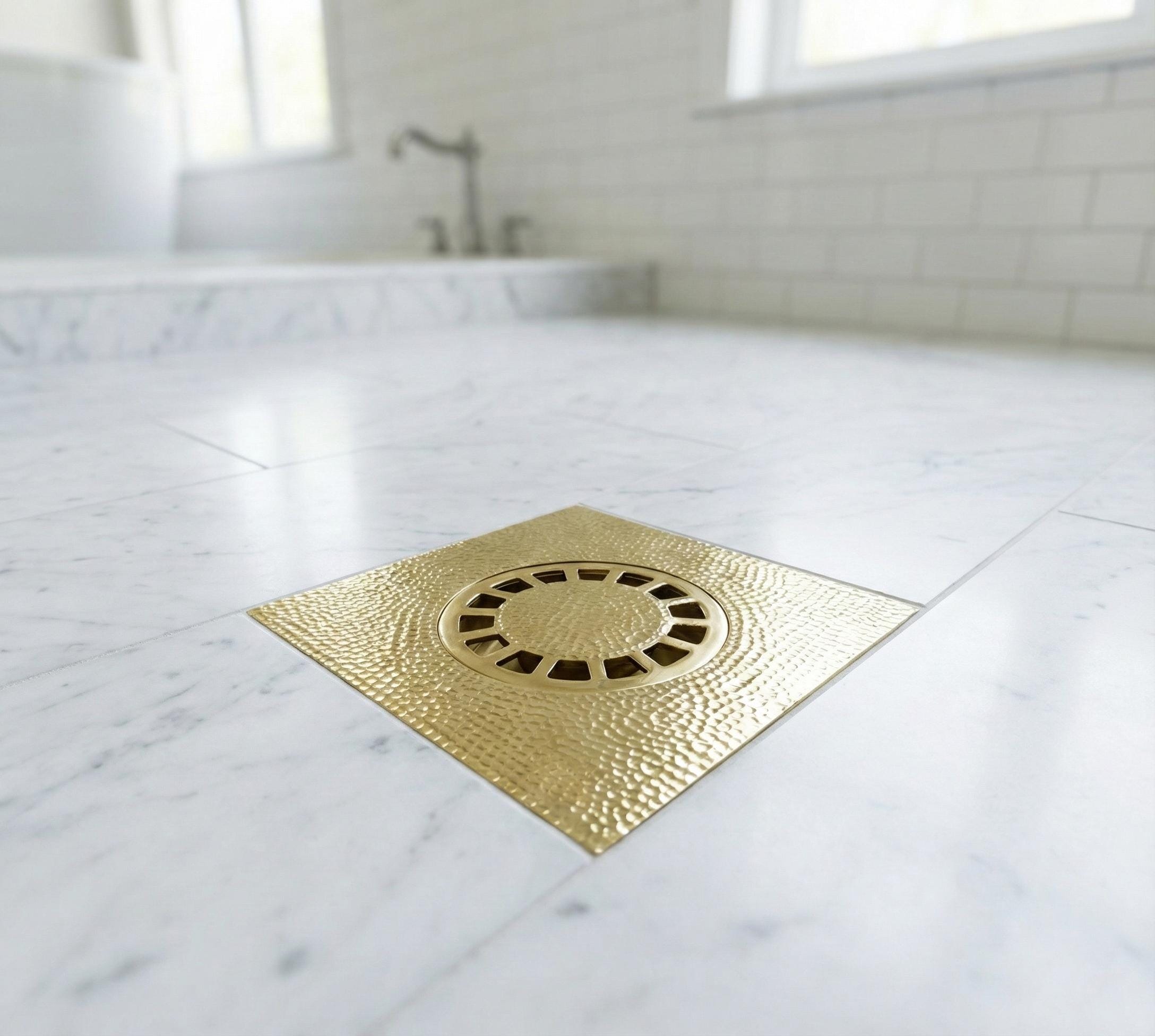 Gold shower drain cover on a marble bathroom floor