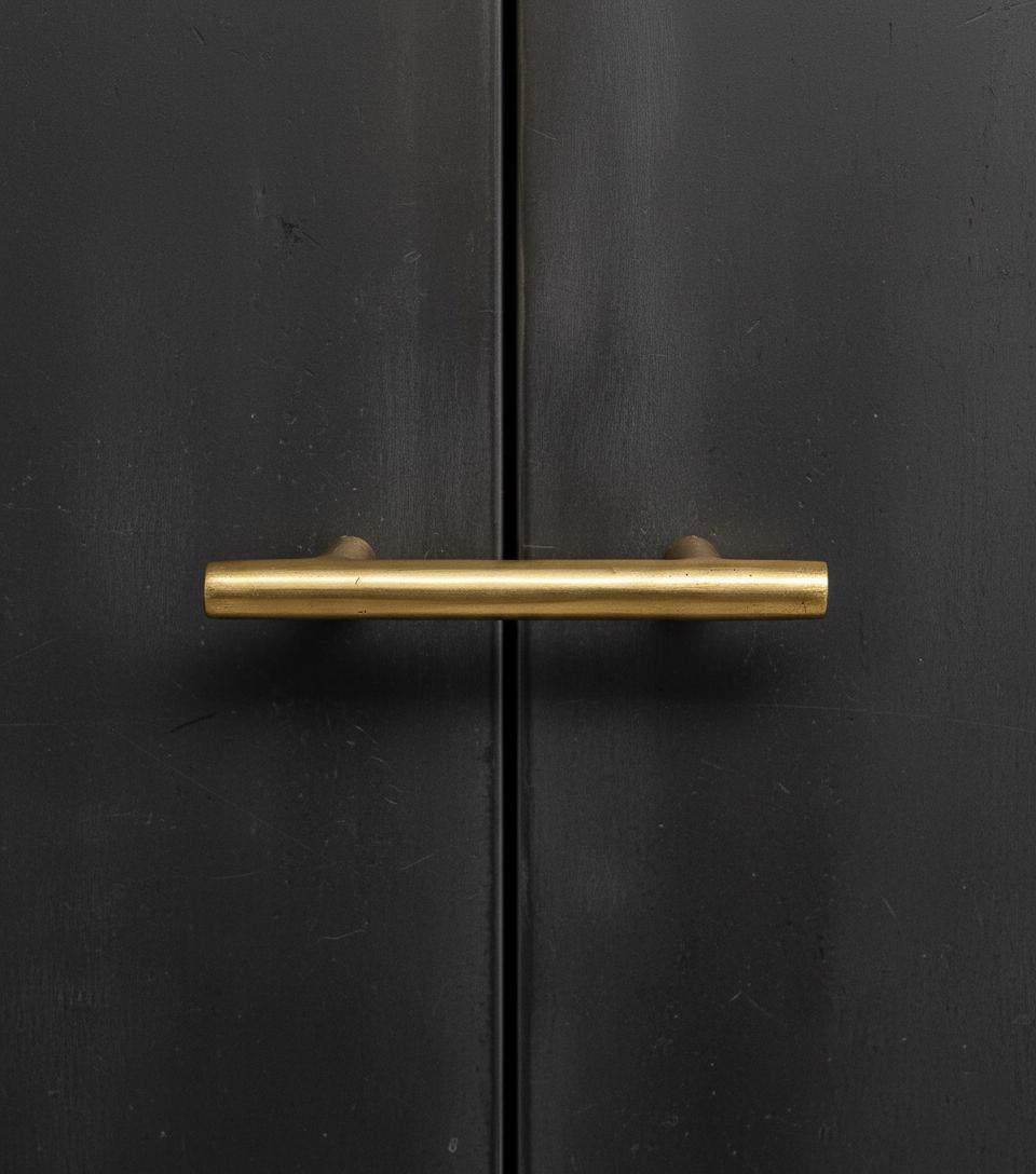Gold cabinet handle on a black cabinet door