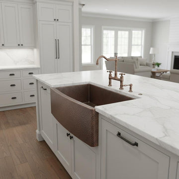 Kitchen with a copper farmhouse sink and white countertops
