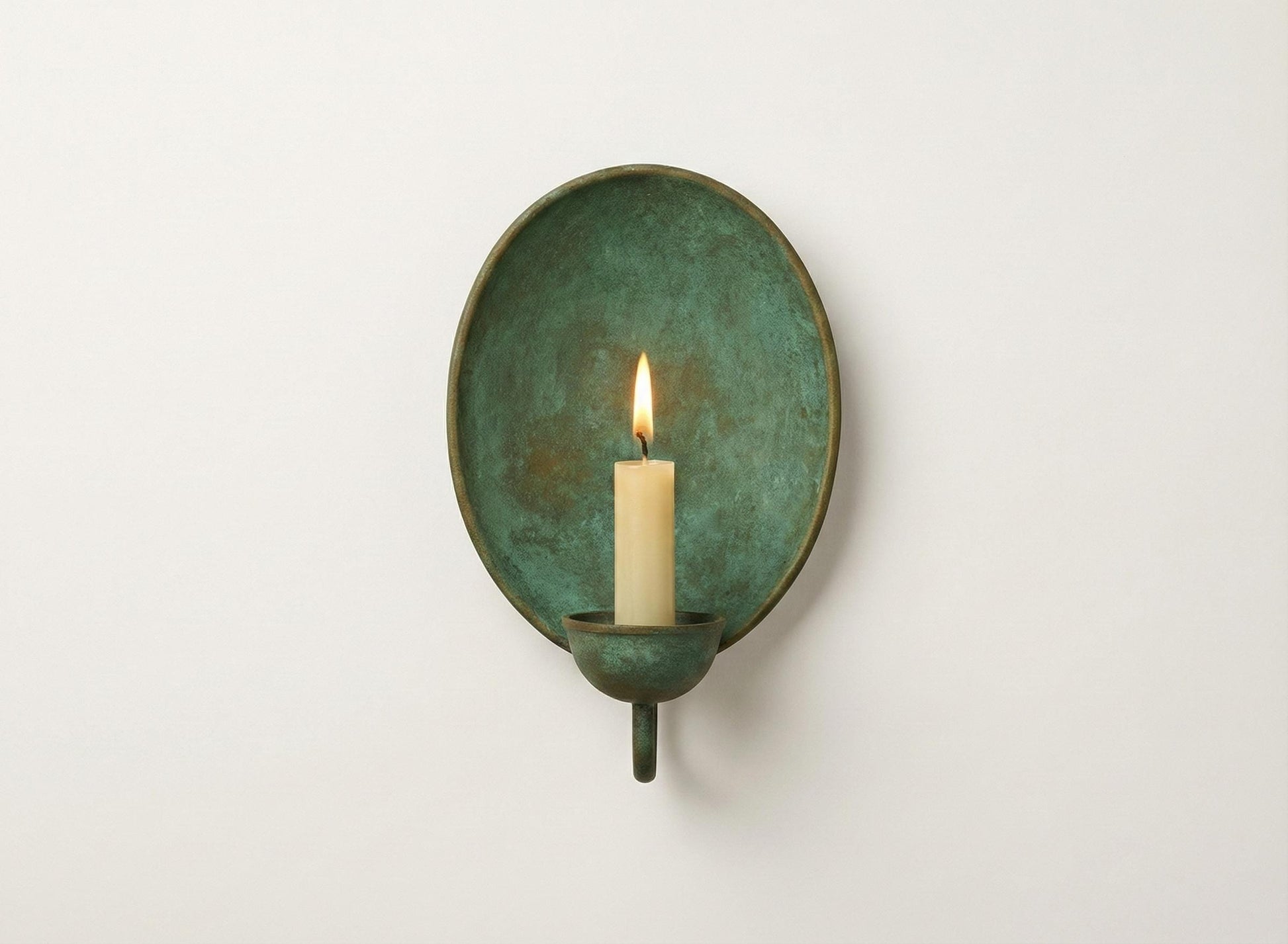 Green wall sconce with a lit candle on a white background