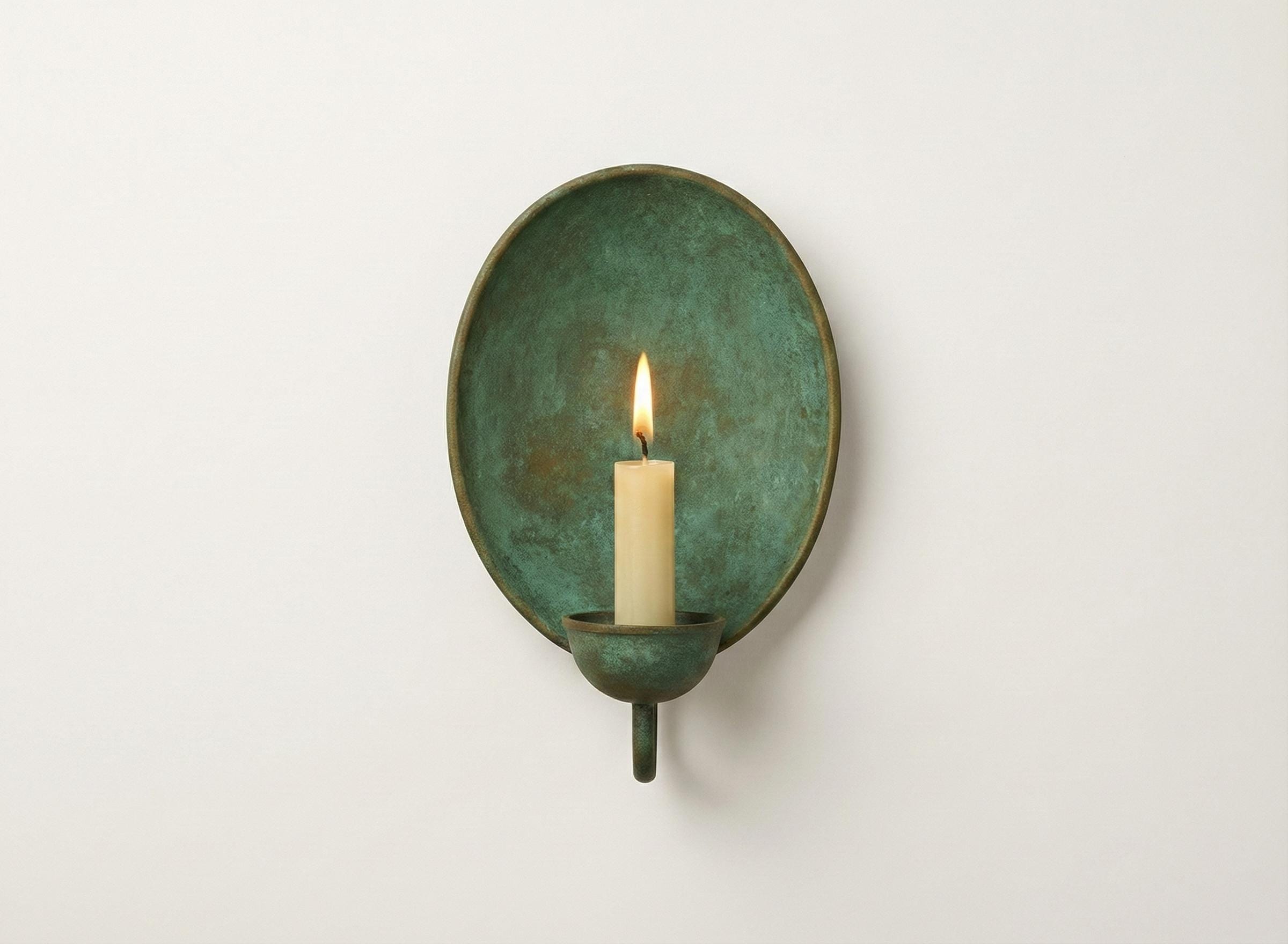 Green wall sconce with a lit candle on a white background