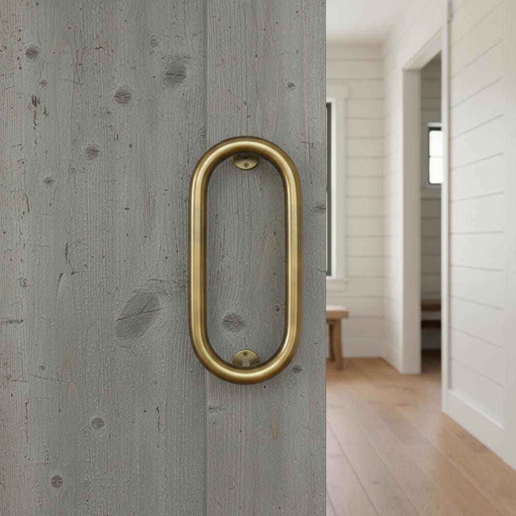 Gold door handle on a gray wooden door with a room visible in the background