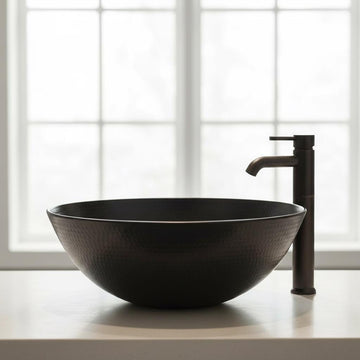 Black ceramic sink with faucet on a white surface with a window in the background