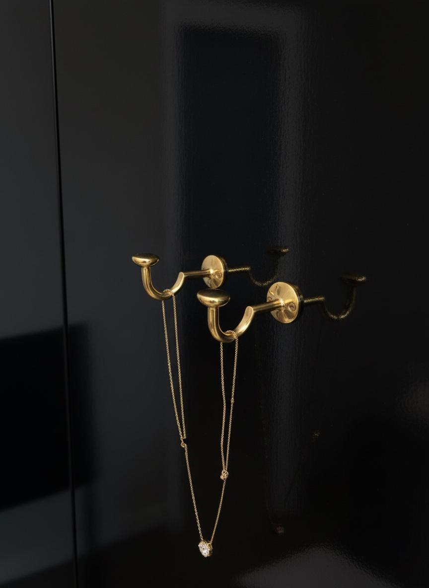 Gold wall-mounted hook set against a black background