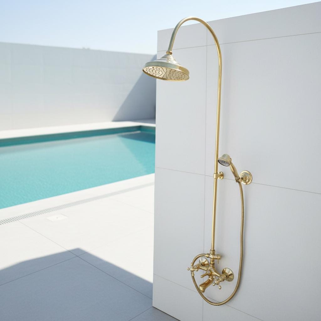 Gold shower set mounted on a white wall with a pool in the background