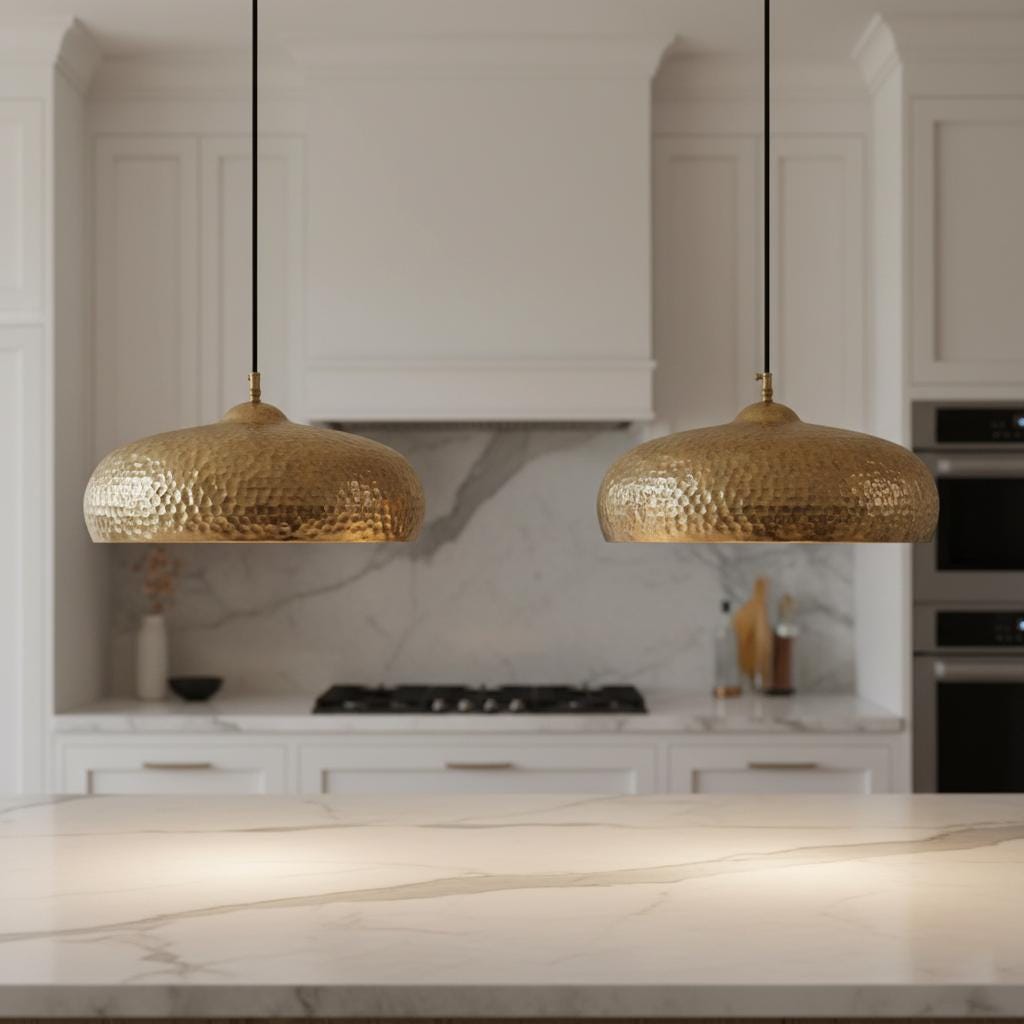 Two gold pendant lights hanging above a kitchen counter.