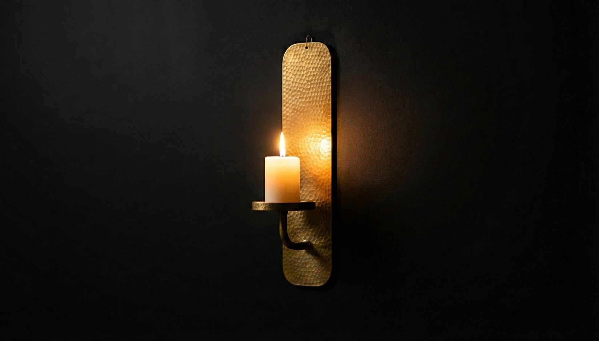 Woven wall sconce with a lit candle on a dark background