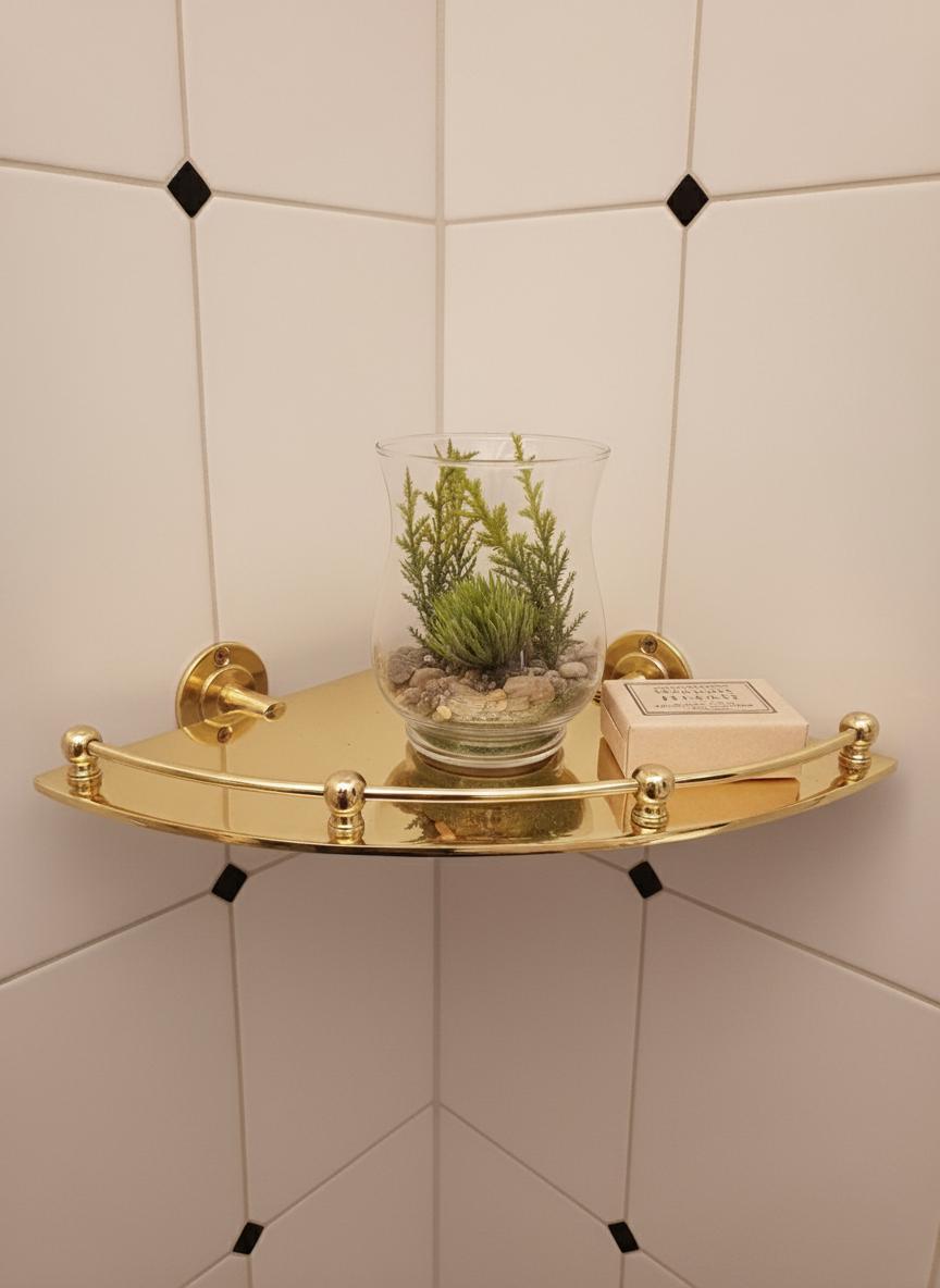Gold corner shelf with a plant and soap on a tiled wall