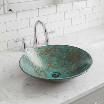 Teal glass sink on a marble countertop with a white tiled wall background