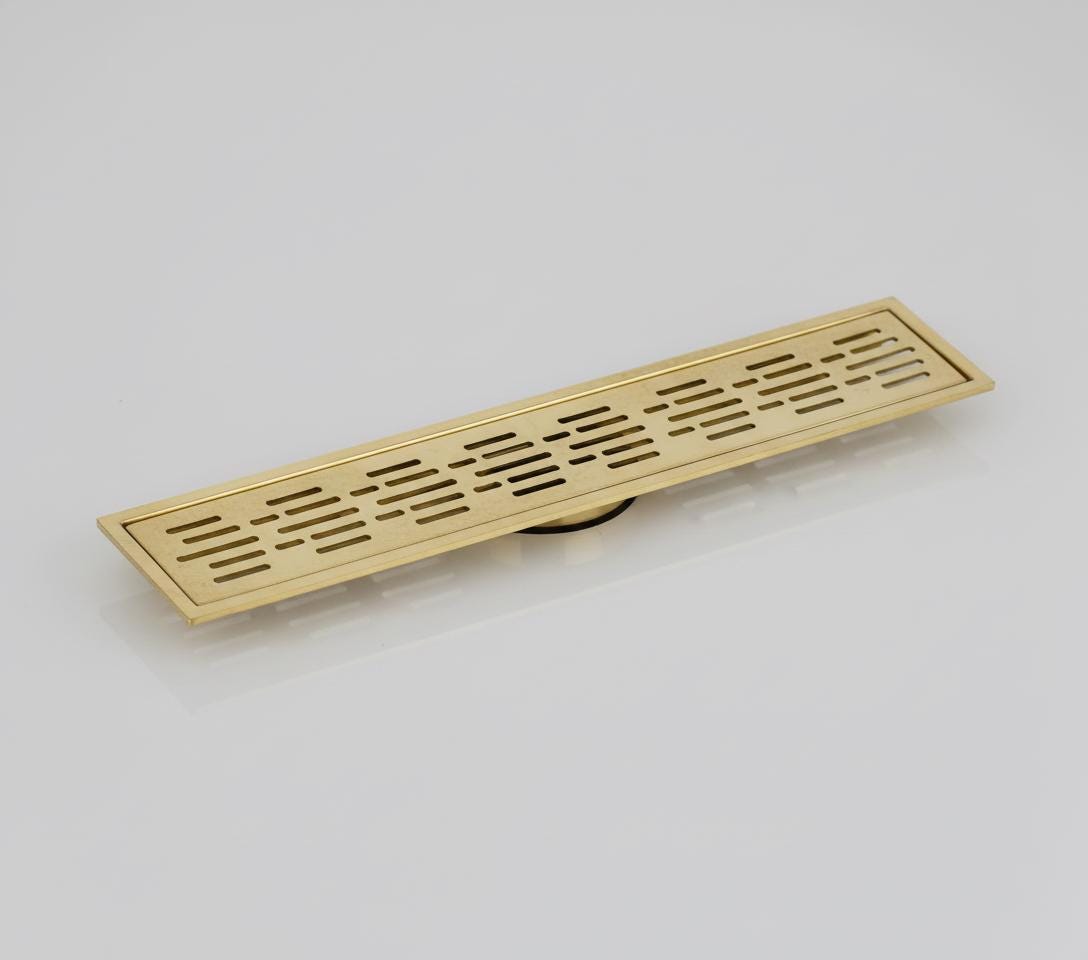 Gold-colored rectangular floor drain cover on a light gray background