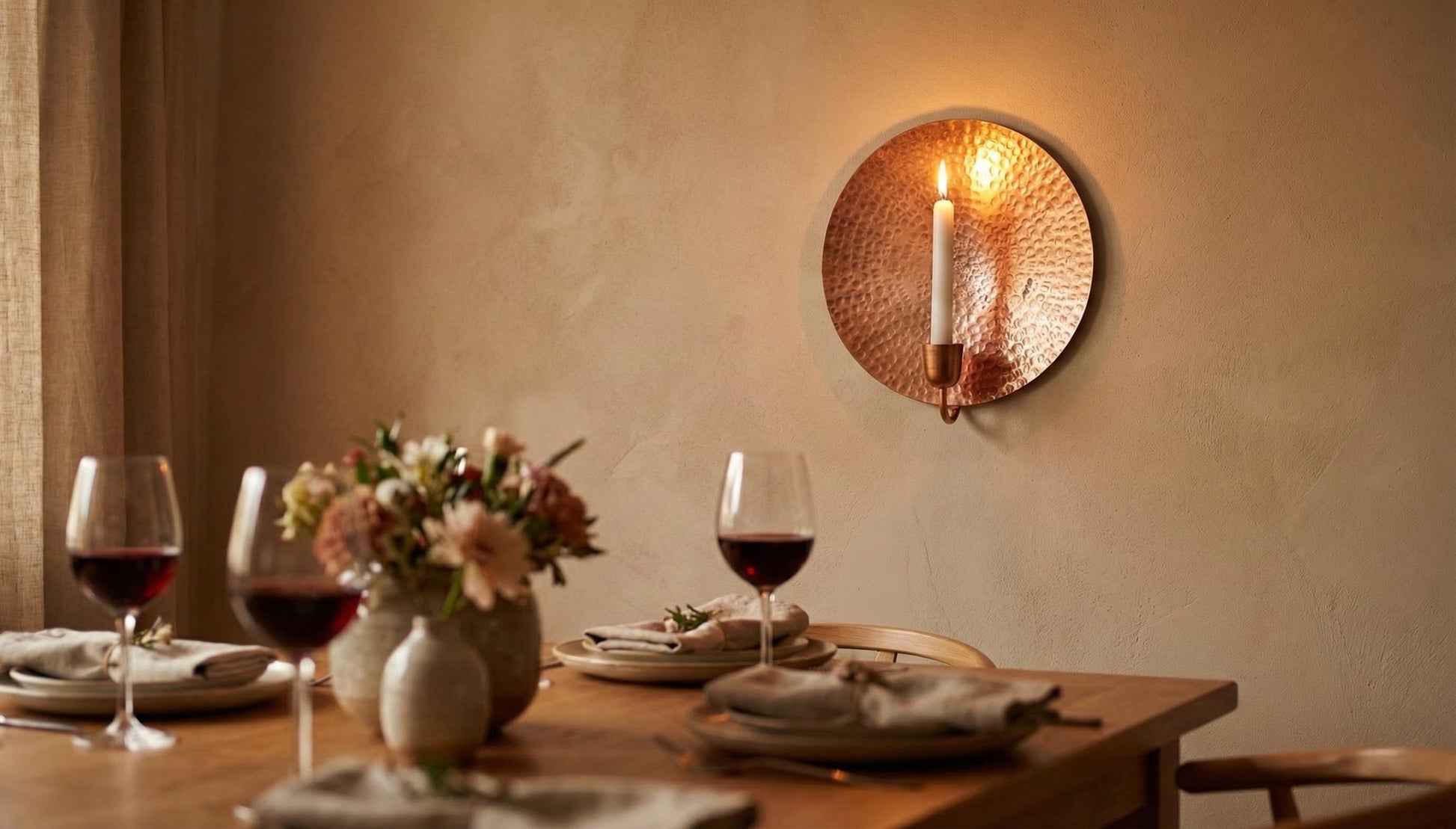 Dining table set with wine glasses, plates, and a vase of flowers, candlelit ambiance.