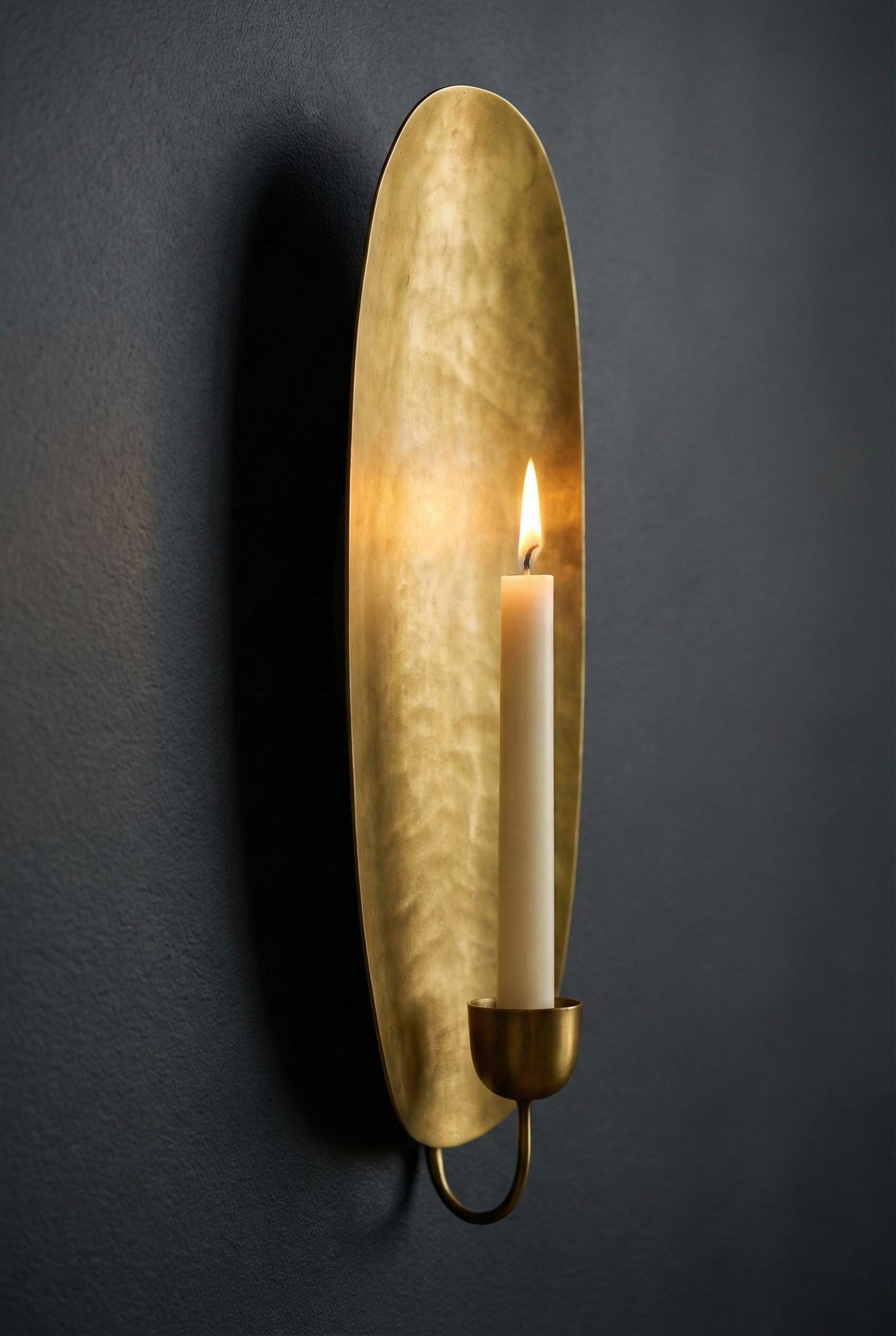 Gold wall sconce with a candle on a dark gray background