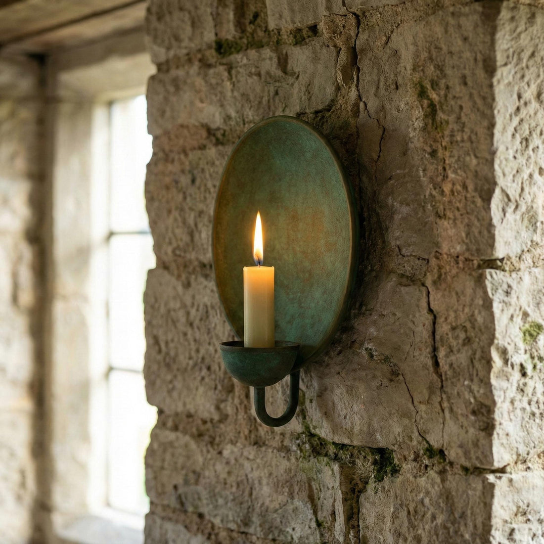 Decorative wall-mounted candle holder with a lit candle on a stone wall.