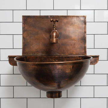 Copper wall-mounted sink with faucet against a white tiled wall