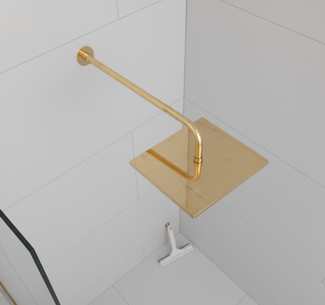Gold shower head and control handle on a tiled bathroom wall