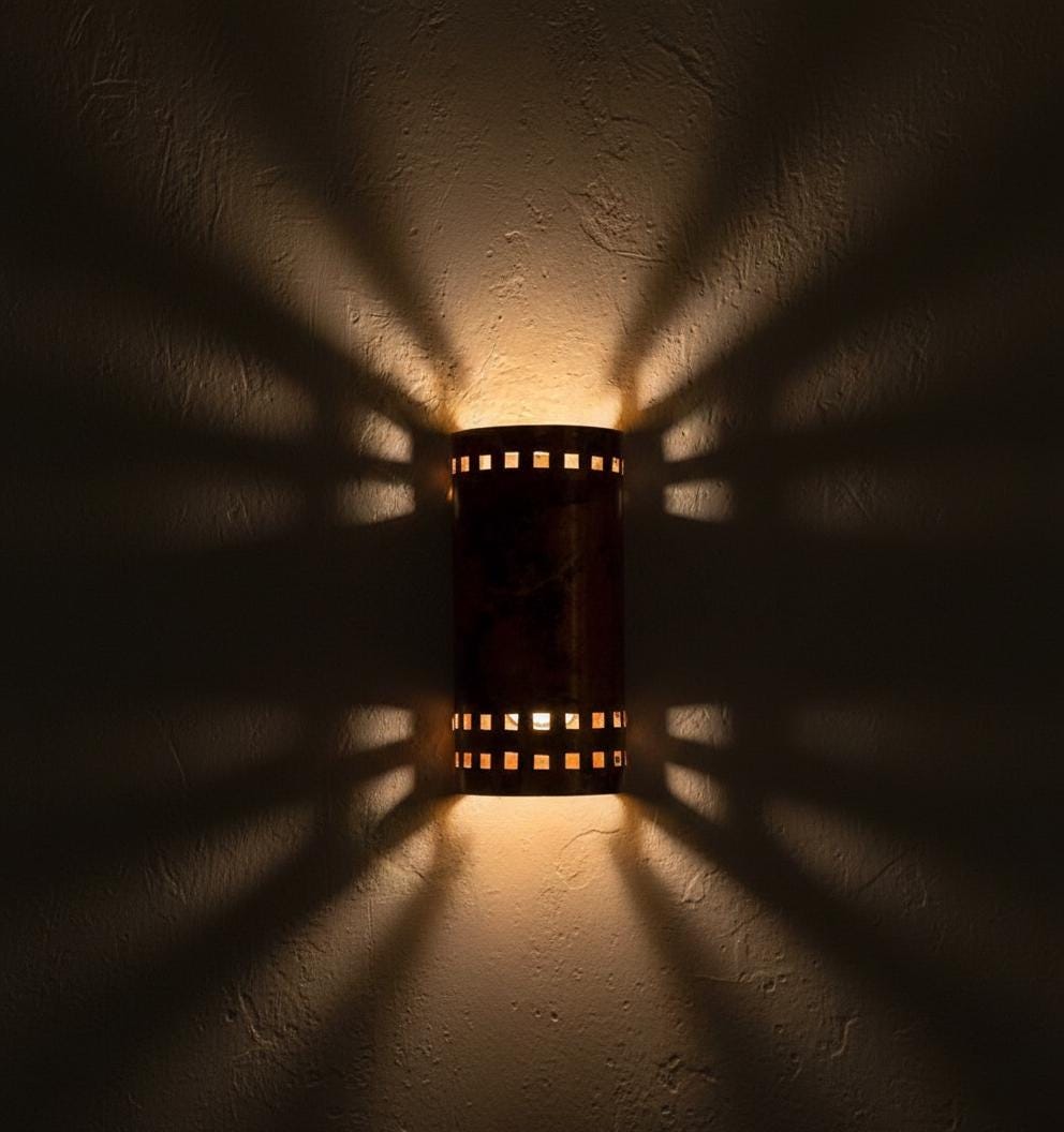 Wall-mounted light fixture casting shadows on a textured wall