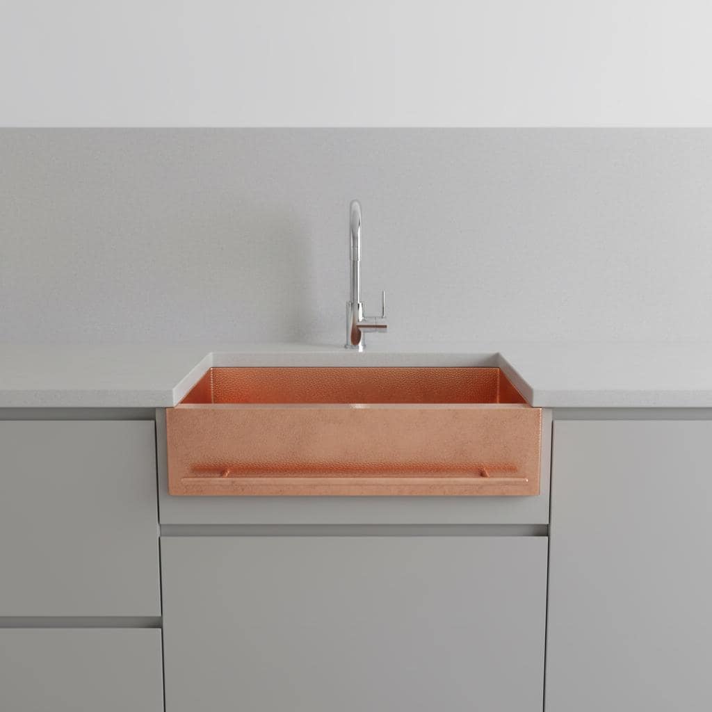 Copper kitchen sink with faucet on a gray countertop