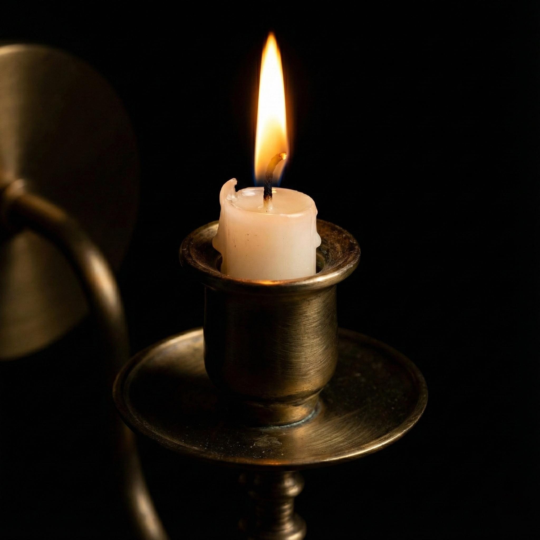 Candle in a metal holder on a black background