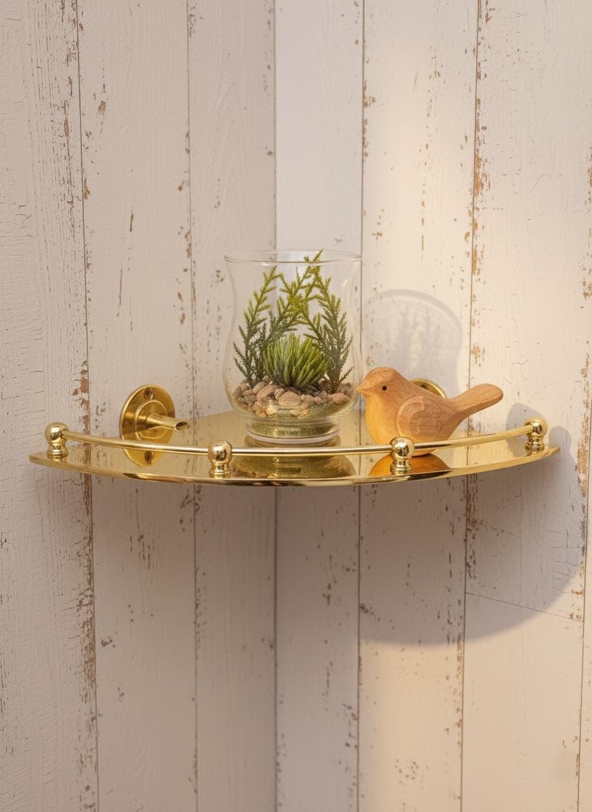 Gold corner shelf with a small plant and wooden bird figurine against a wooden wall.