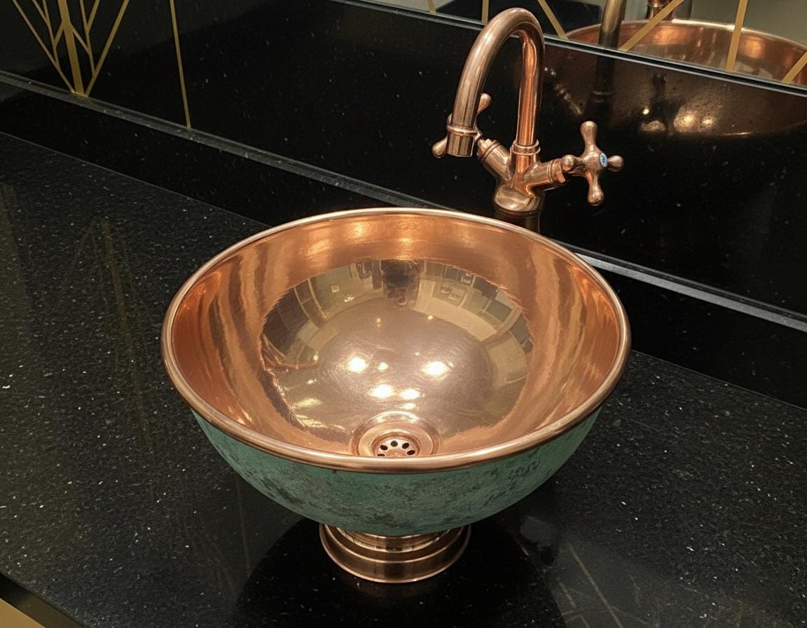 Copper sink with faucet on a black countertop