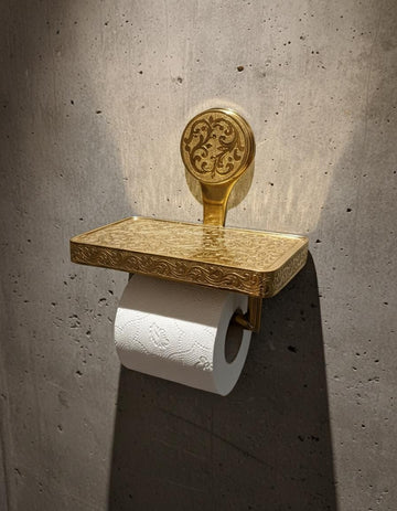 Decorative gold toilet paper holder with a concrete wall background