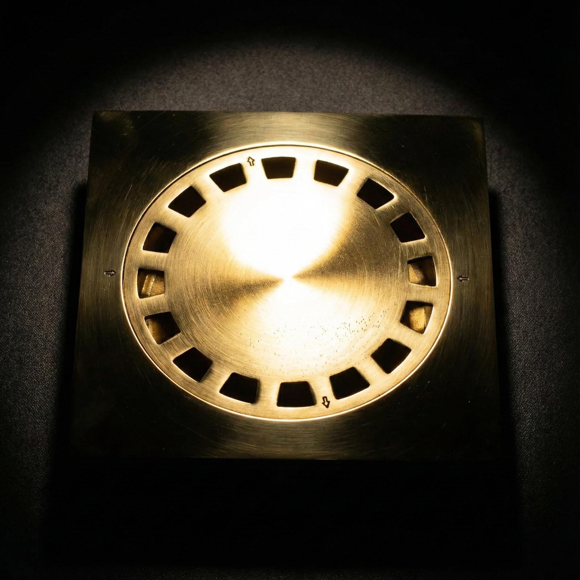 Brass-colored light fixture with circular design on a dark background