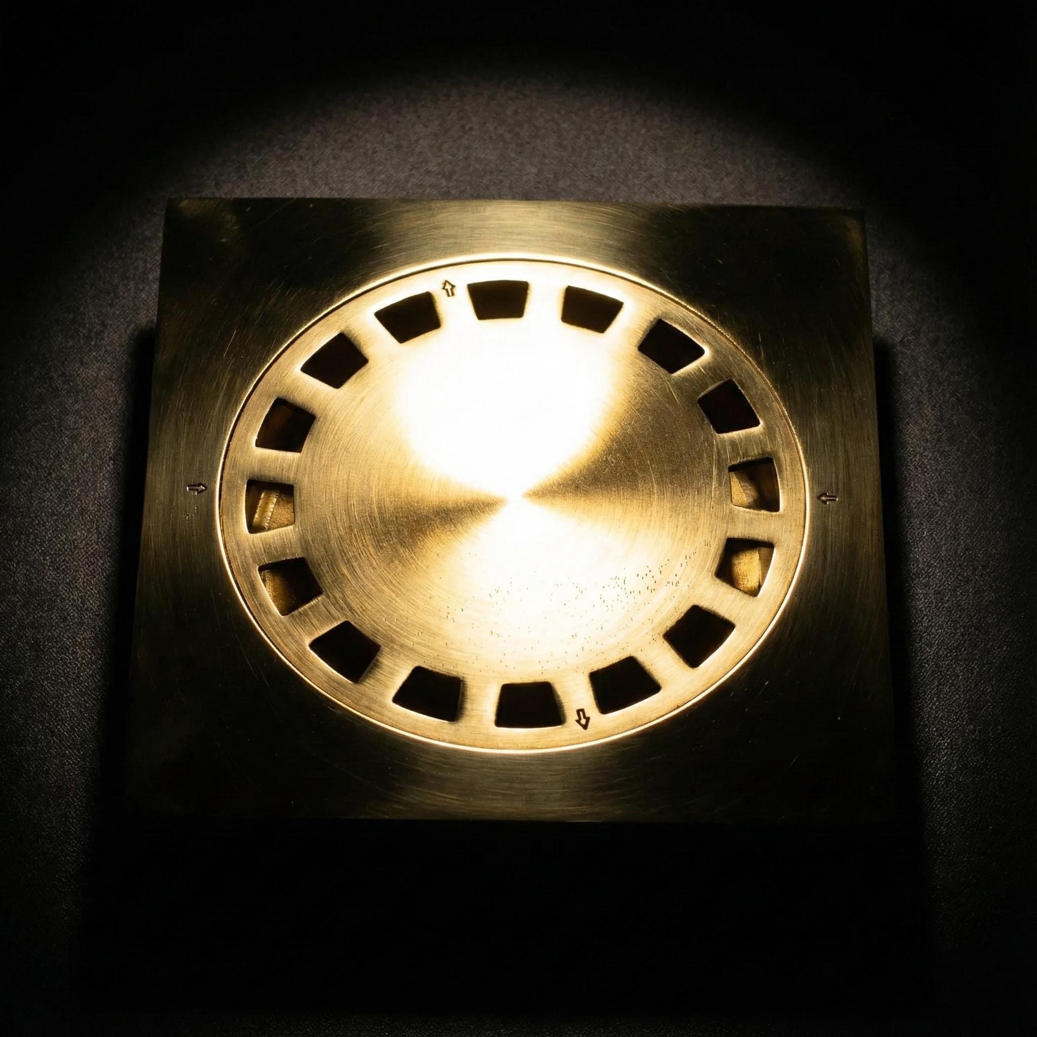 Brass-colored light fixture with circular design on a dark background