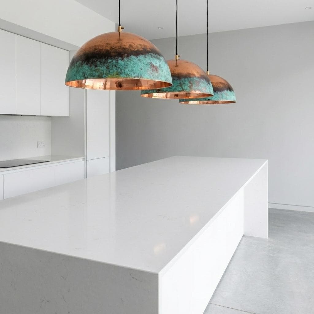 Modern kitchen with copper pendant lights on a white island.