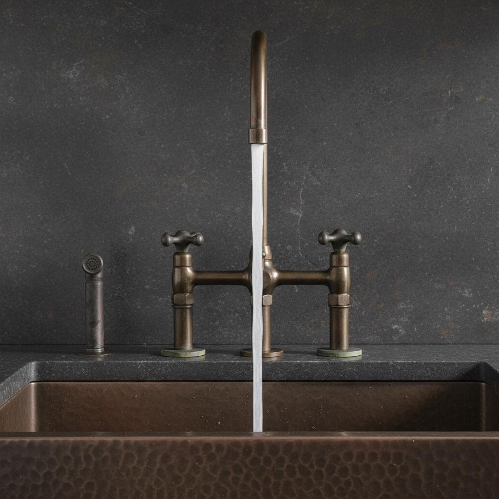 Bronze faucet and handles on a dark stone sink with a dark gray wall background
