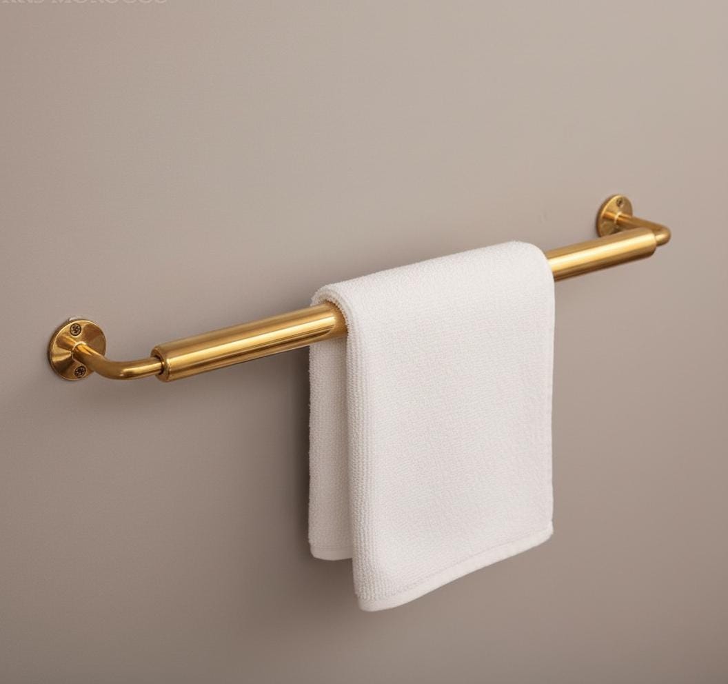 Gold towel bar with a white towel on a beige wall