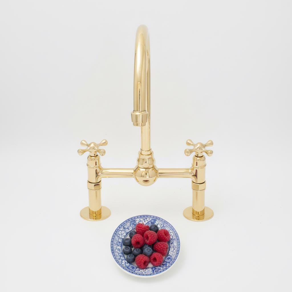 Gold kitchen faucet with a bowl of berries on a white background