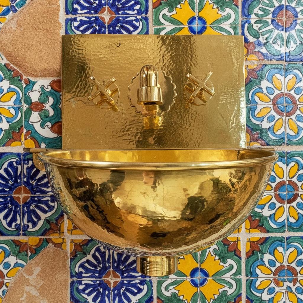 Gold wall-mounted basin with decorative tiles in the background