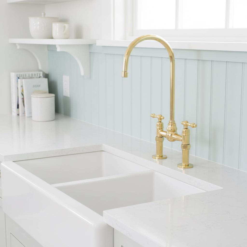 Gold kitchen faucet on a marble countertop with a gray background