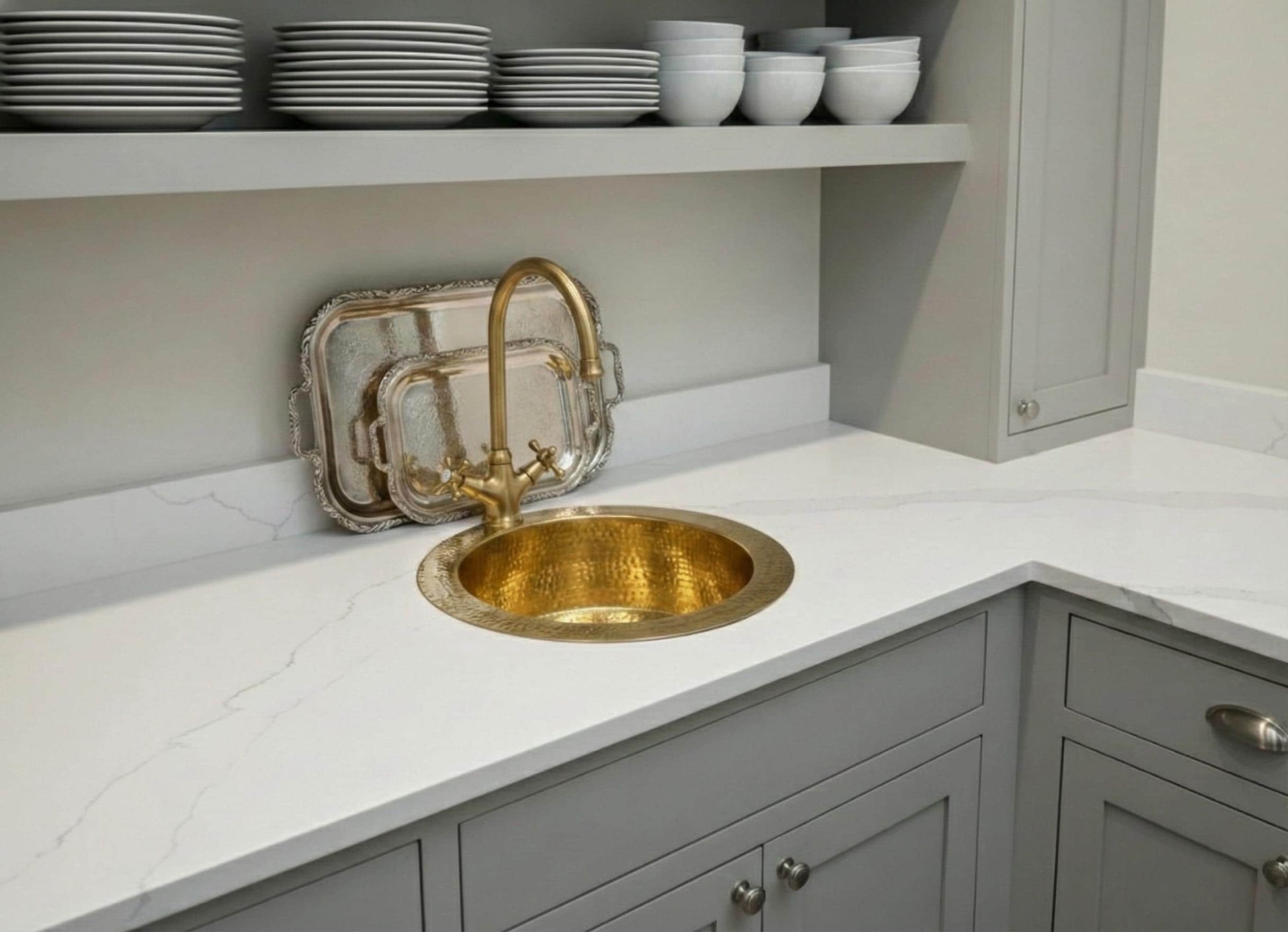 Kitchen with a gold sink and faucet on a white countertop.