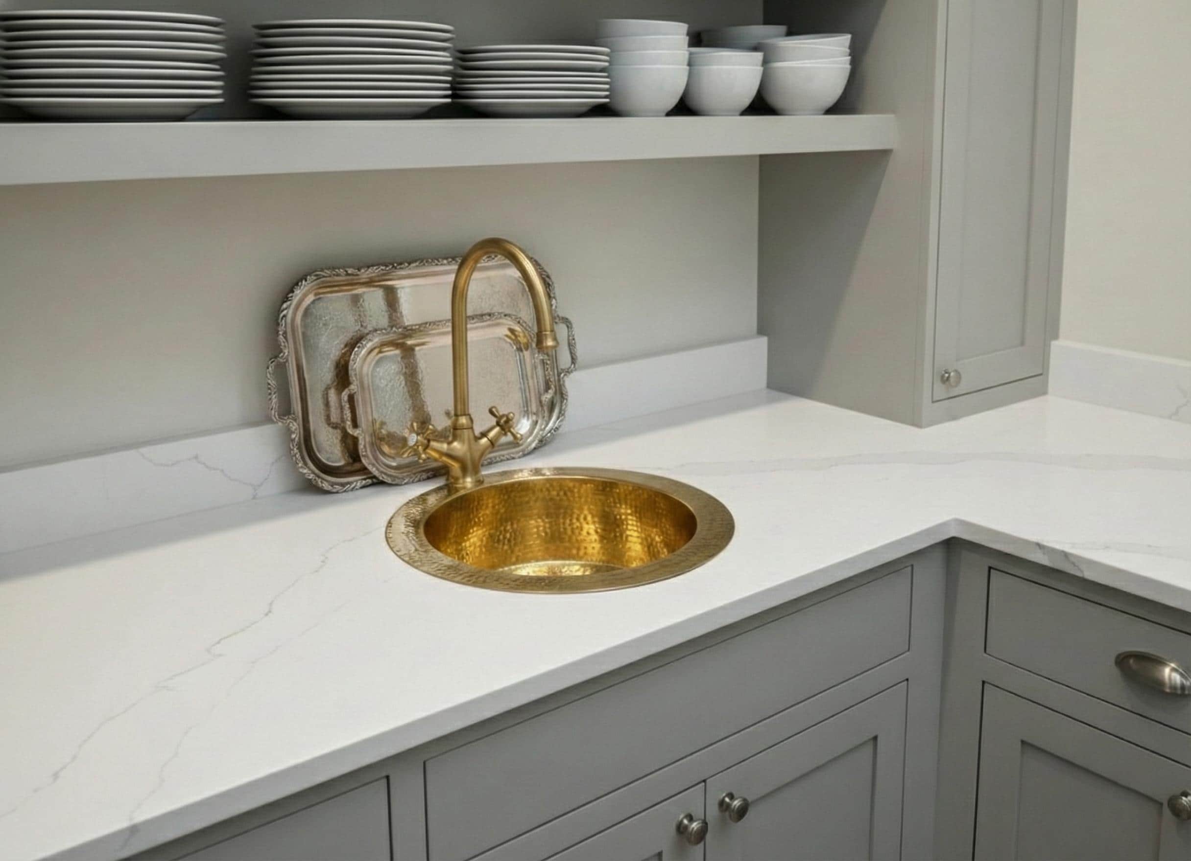 Kitchen with a gold sink and faucet on a white countertop.