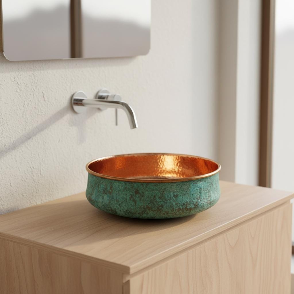 Bathroom sink with copper interior and green exterior on a wooden cabinet